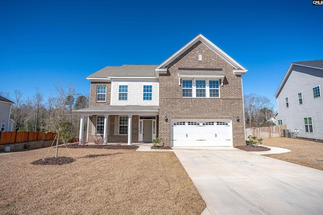 traditional-style house featuring a front lawn, fence, concrete driveway, a garage, and brick siding