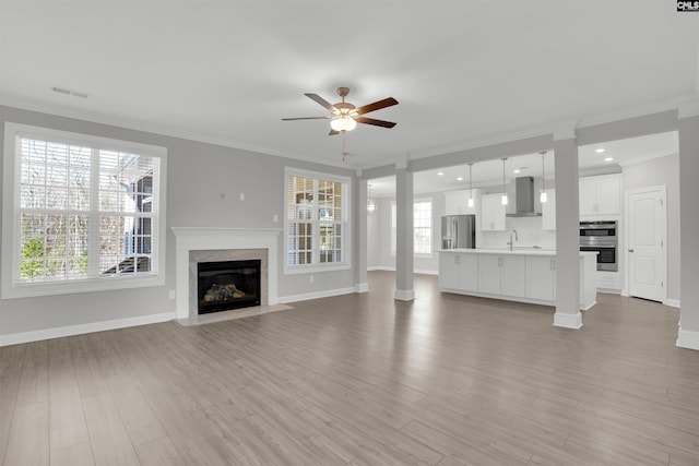 unfurnished living room with ceiling fan, crown molding, visible vents, and light wood-type flooring