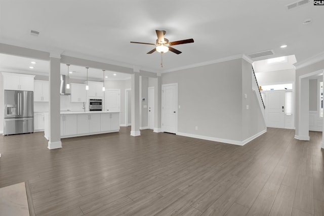 unfurnished living room featuring crown molding, baseboards, dark wood-type flooring, decorative columns, and a ceiling fan