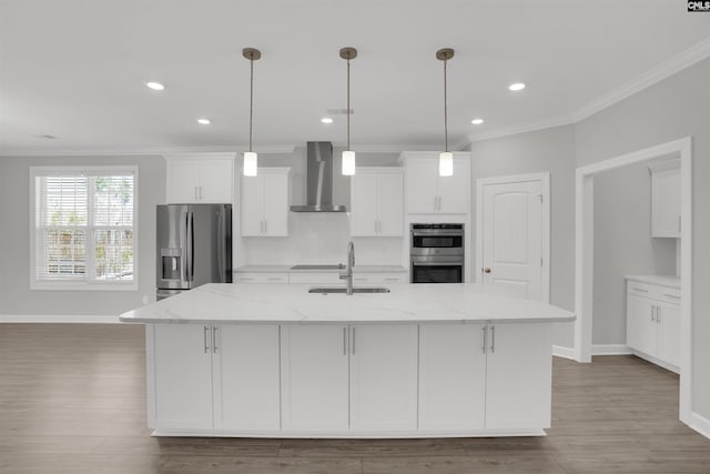 kitchen with a sink, stainless steel appliances, wall chimney exhaust hood, and white cabinetry