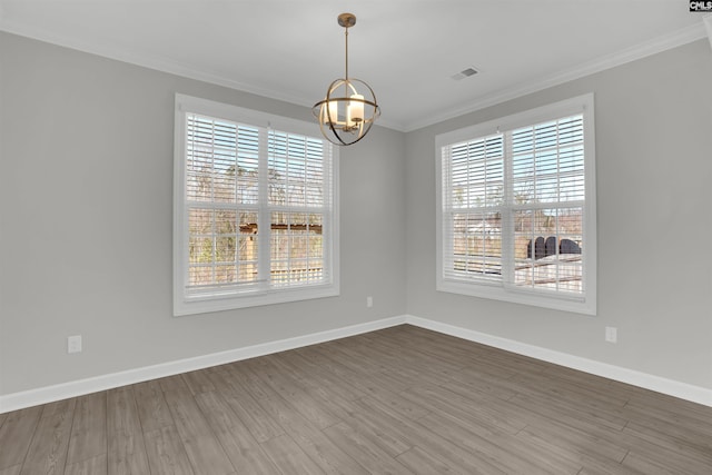 unfurnished room with visible vents, crown molding, baseboards, wood finished floors, and a notable chandelier