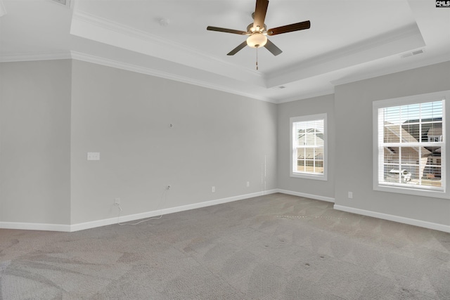 empty room with visible vents, baseboards, carpet, crown molding, and a raised ceiling