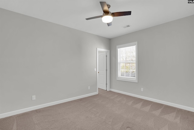 carpeted spare room with baseboards, visible vents, and ceiling fan