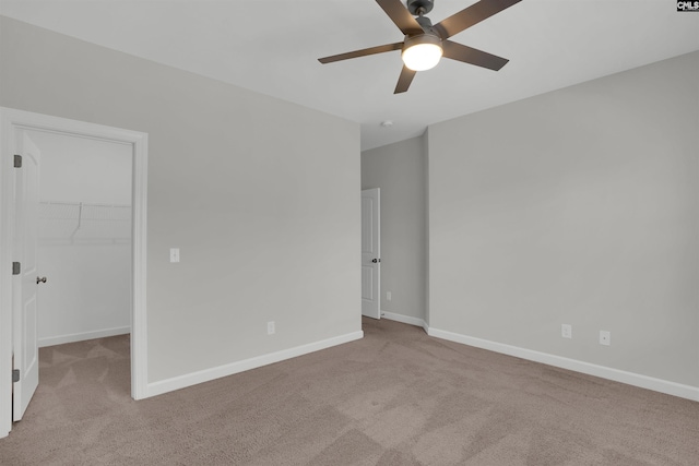 unfurnished bedroom with a walk in closet, baseboards, and carpet