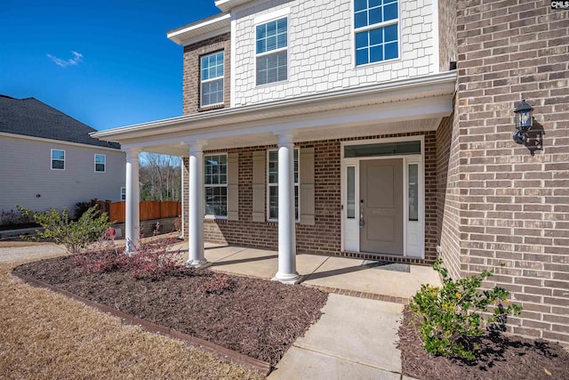 property entrance with covered porch and brick siding