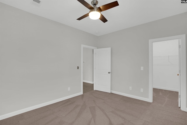 unfurnished bedroom featuring a spacious closet, carpet flooring, visible vents, and baseboards