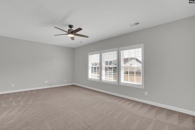 carpeted spare room with visible vents, baseboards, and ceiling fan