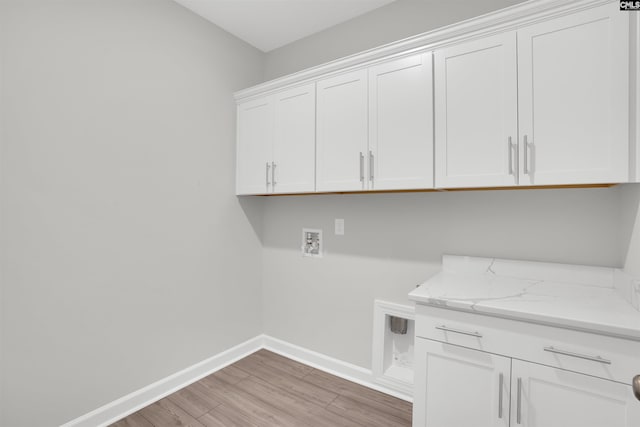 laundry area featuring light wood-style floors, hookup for a washing machine, cabinet space, and baseboards