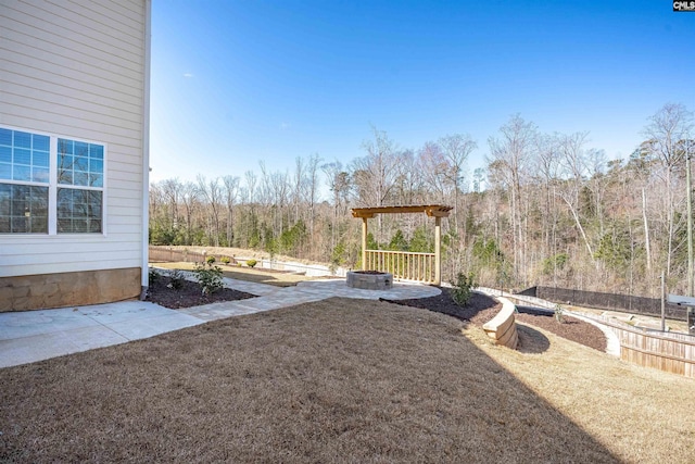 view of yard featuring a forest view and an outdoor fire pit