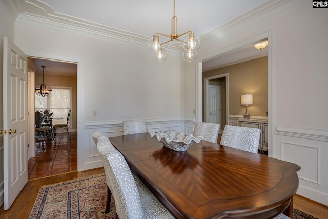 dining space featuring a chandelier, a wainscoted wall, crown molding, and wood finished floors