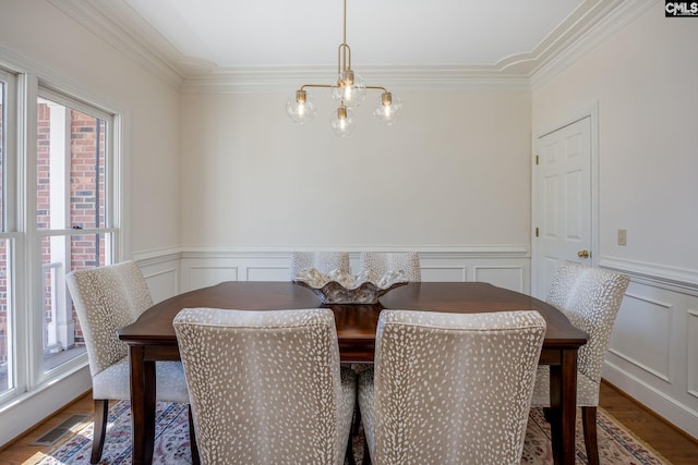 dining area featuring an inviting chandelier, crown molding, wood finished floors, and visible vents