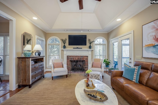living room with wood finished floors, recessed lighting, crown molding, lofted ceiling, and a brick fireplace
