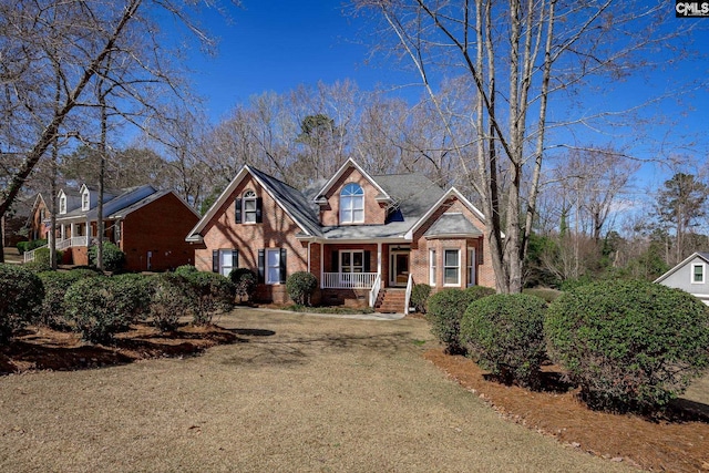 view of front of house with a porch, dirt driveway, a front yard, crawl space, and brick siding