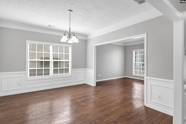 unfurnished dining area with dark wood finished floors, a chandelier, a textured ceiling, and crown molding