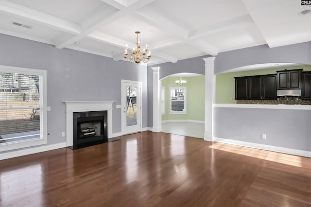 unfurnished living room with visible vents, a chandelier, a fireplace, wood finished floors, and ornate columns