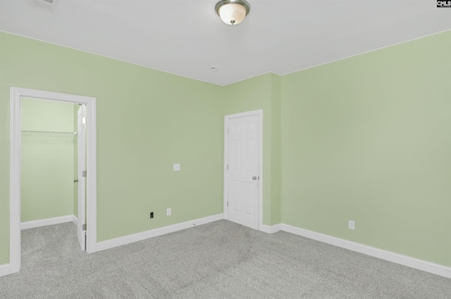 unfurnished bedroom featuring a walk in closet, carpet floors, baseboards, and a closet