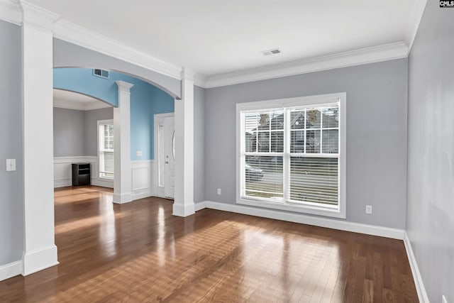 unfurnished room with decorative columns, arched walkways, visible vents, and dark wood-style flooring