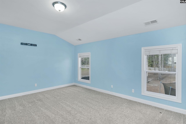 empty room featuring visible vents, lofted ceiling, carpet, and baseboards