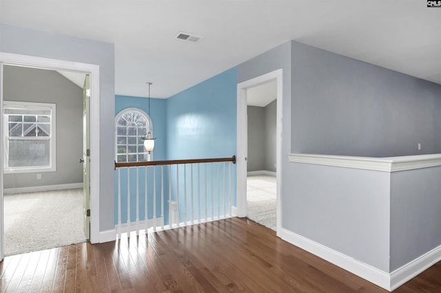 unfurnished room featuring hardwood / wood-style flooring, baseboards, and visible vents