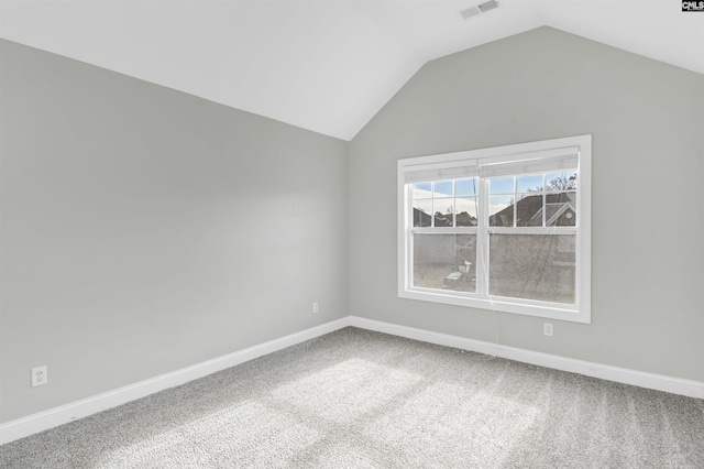 carpeted spare room featuring vaulted ceiling, baseboards, and visible vents