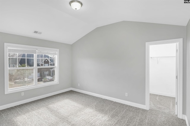 carpeted empty room with visible vents, lofted ceiling, and baseboards