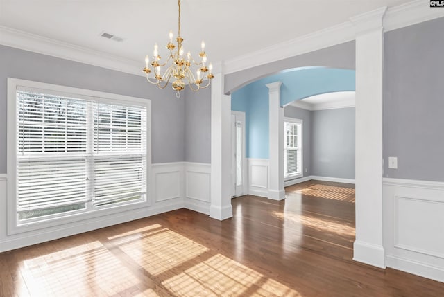 unfurnished dining area with visible vents, ornamental molding, wainscoting, wood finished floors, and arched walkways