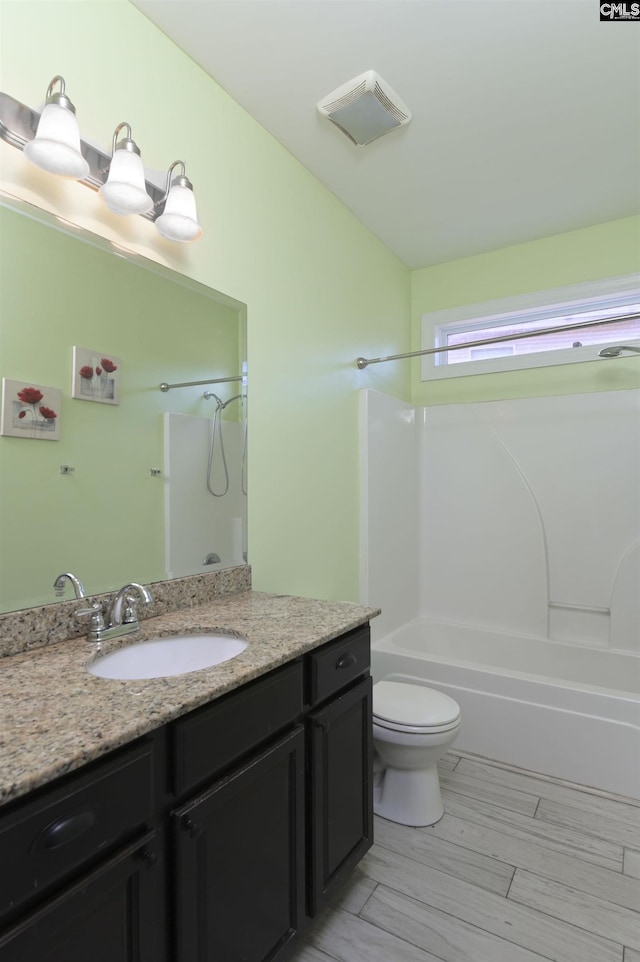 bathroom featuring visible vents, toilet, lofted ceiling, shower / bathing tub combination, and vanity