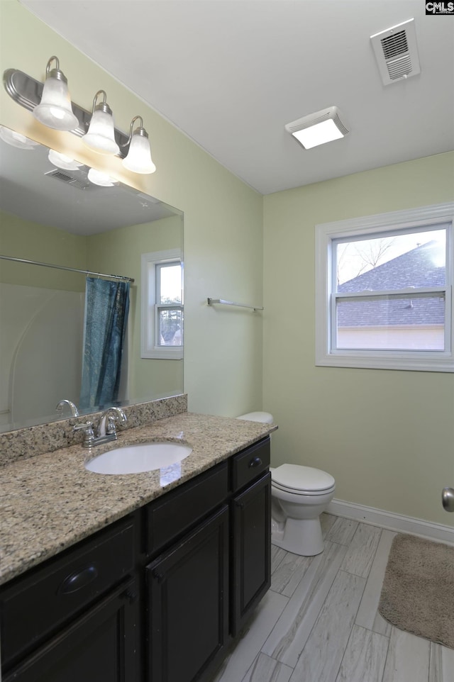 bathroom featuring a wealth of natural light, visible vents, toilet, and baseboards