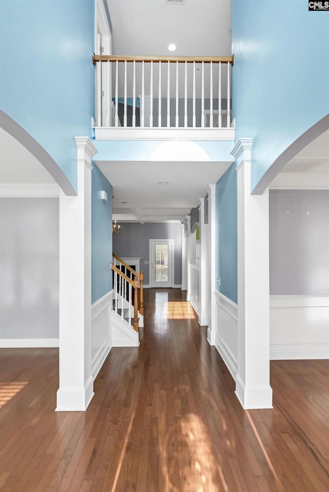 entryway featuring ornamental molding, stairs, wood-type flooring, and decorative columns