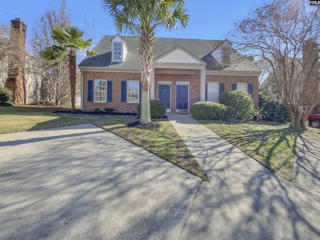 cape cod home with a front lawn, brick siding, and a shingled roof