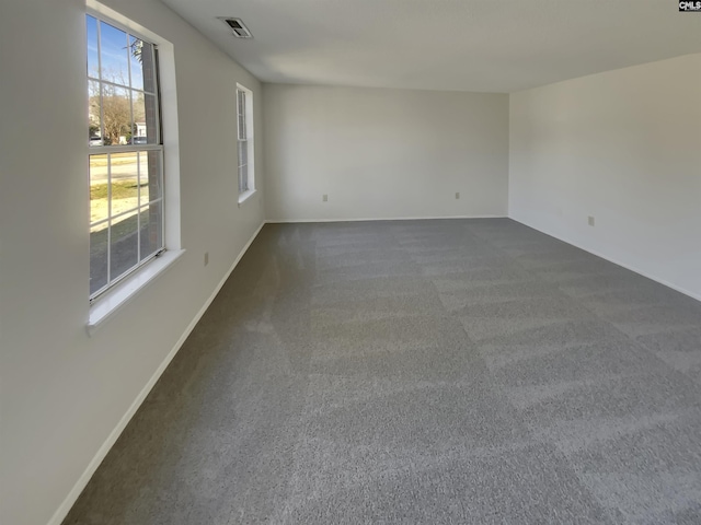 empty room featuring visible vents, baseboards, and dark colored carpet