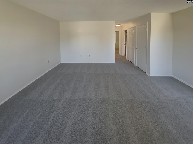 empty room with dark colored carpet and baseboards