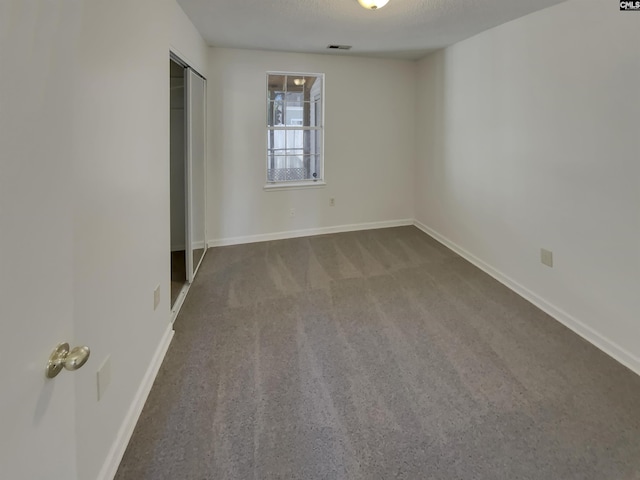 unfurnished bedroom featuring a textured ceiling, carpet, visible vents, and baseboards