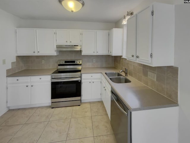 kitchen featuring under cabinet range hood, a sink, tasteful backsplash, appliances with stainless steel finishes, and white cabinets