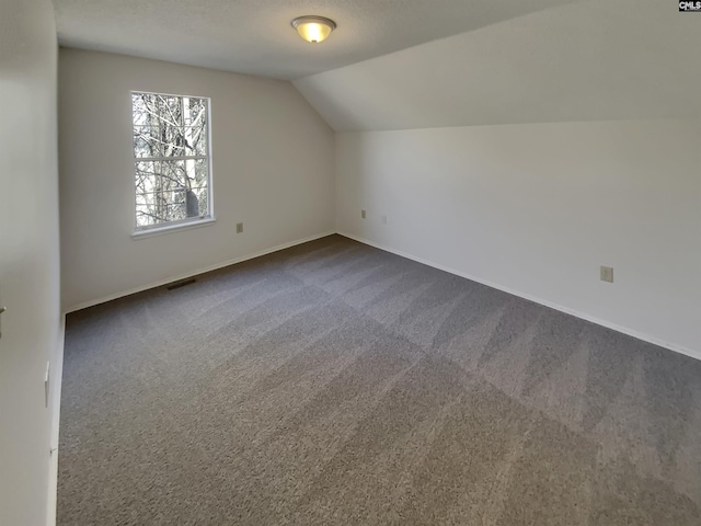 bonus room with vaulted ceiling, baseboards, visible vents, and dark carpet