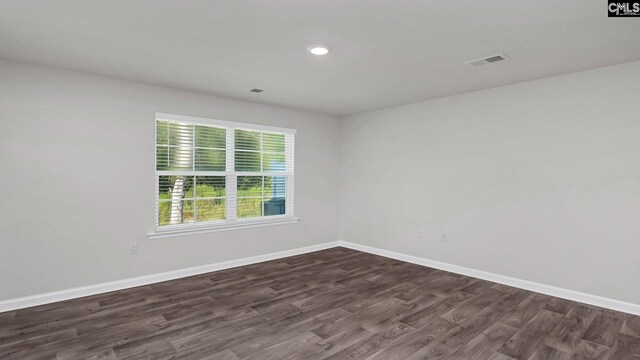 spare room featuring dark wood-type flooring, baseboards, and visible vents