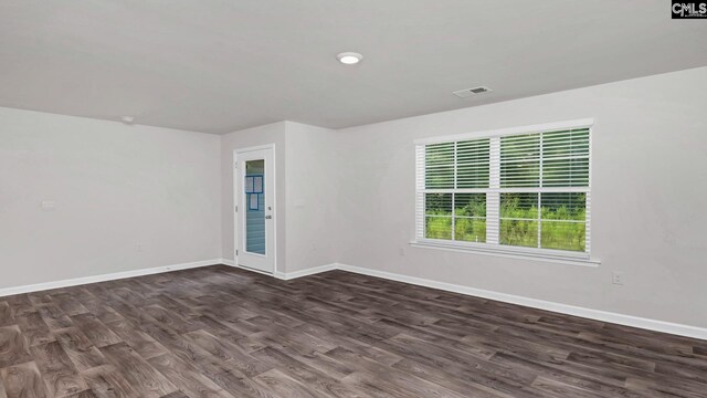 empty room with baseboards, visible vents, and dark wood-style flooring