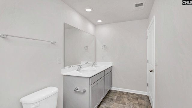 full bathroom featuring double vanity, visible vents, toilet, and a sink