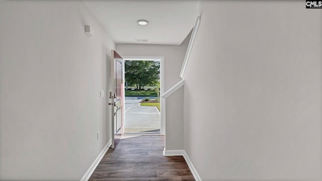 doorway with dark wood-type flooring, visible vents, and baseboards