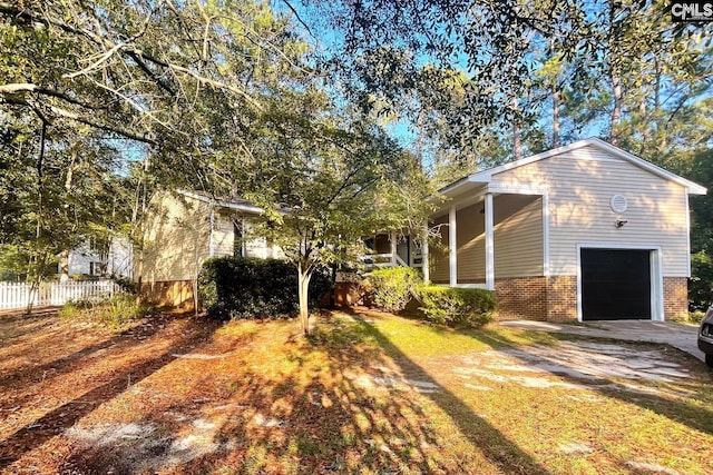 view of side of property featuring a yard, fence, brick siding, and driveway