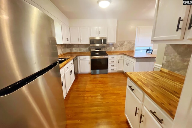 kitchen with white cabinetry, stainless steel appliances, light wood finished floors, decorative backsplash, and wooden counters