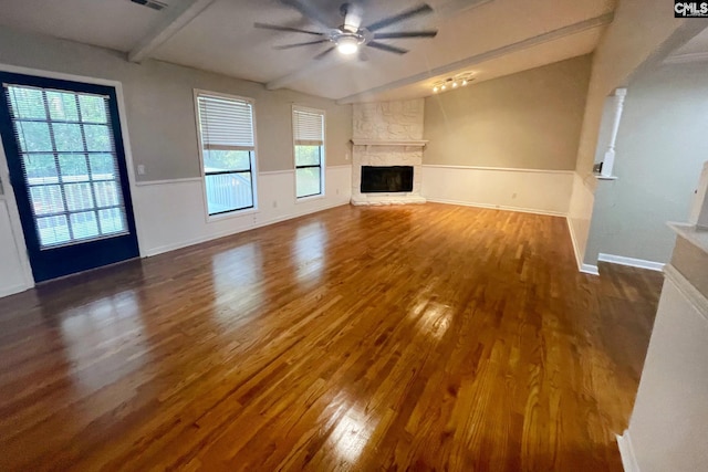 unfurnished living room with lofted ceiling with beams, wood finished floors, a fireplace, baseboards, and ceiling fan