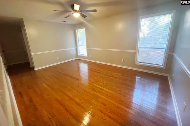 spare room with visible vents, ceiling fan, baseboards, and wood finished floors