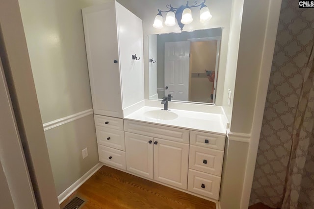 bathroom featuring visible vents, vanity, baseboards, and wood finished floors