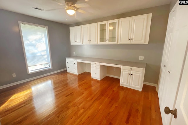 unfurnished office with a ceiling fan, baseboards, visible vents, built in study area, and light wood-type flooring