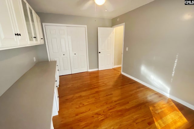 unfurnished bedroom featuring ceiling fan, wood finished floors, a closet, and baseboards