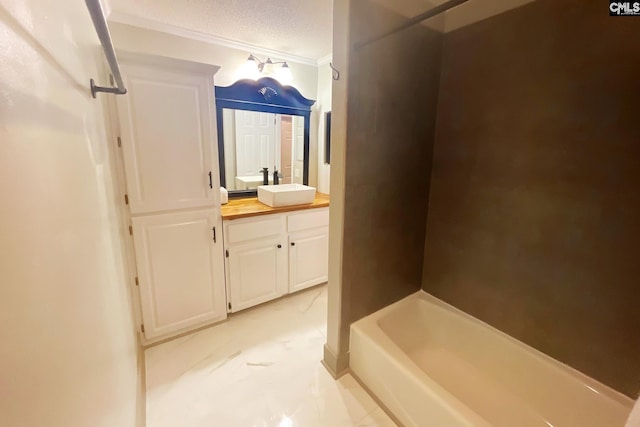 full bath with a textured ceiling, vanity, and crown molding