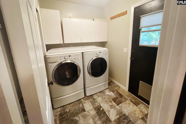 clothes washing area featuring baseboards, cabinet space, and washing machine and dryer