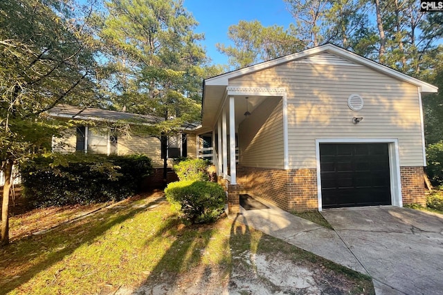 view of side of home featuring a garage, brick siding, and driveway