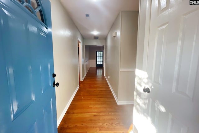 corridor with visible vents, baseboards, and light wood-style floors